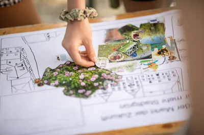 Zu sehen ist ein Arbeitsblatt auf das eine Hand etwas klebt.