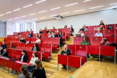 Die Aufnahme zeigt einen Hörsaal, in dem Personen sitzen.