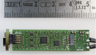 Eine kleine elektronische Platine liegt neben einem Lineal, das die Größe der Platine verdeutlicht.