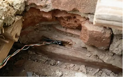 Wandöffnung mit sichtbaren Drähten und einem Holzstück